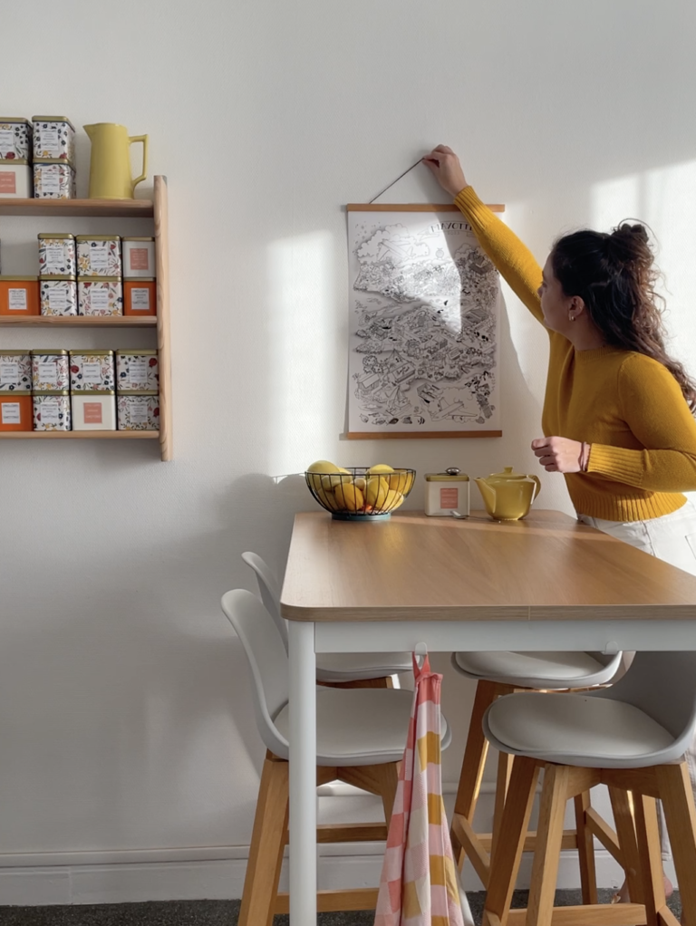 Illustratrice accrochant une affiche illustrée personnalisée dans un intérieur